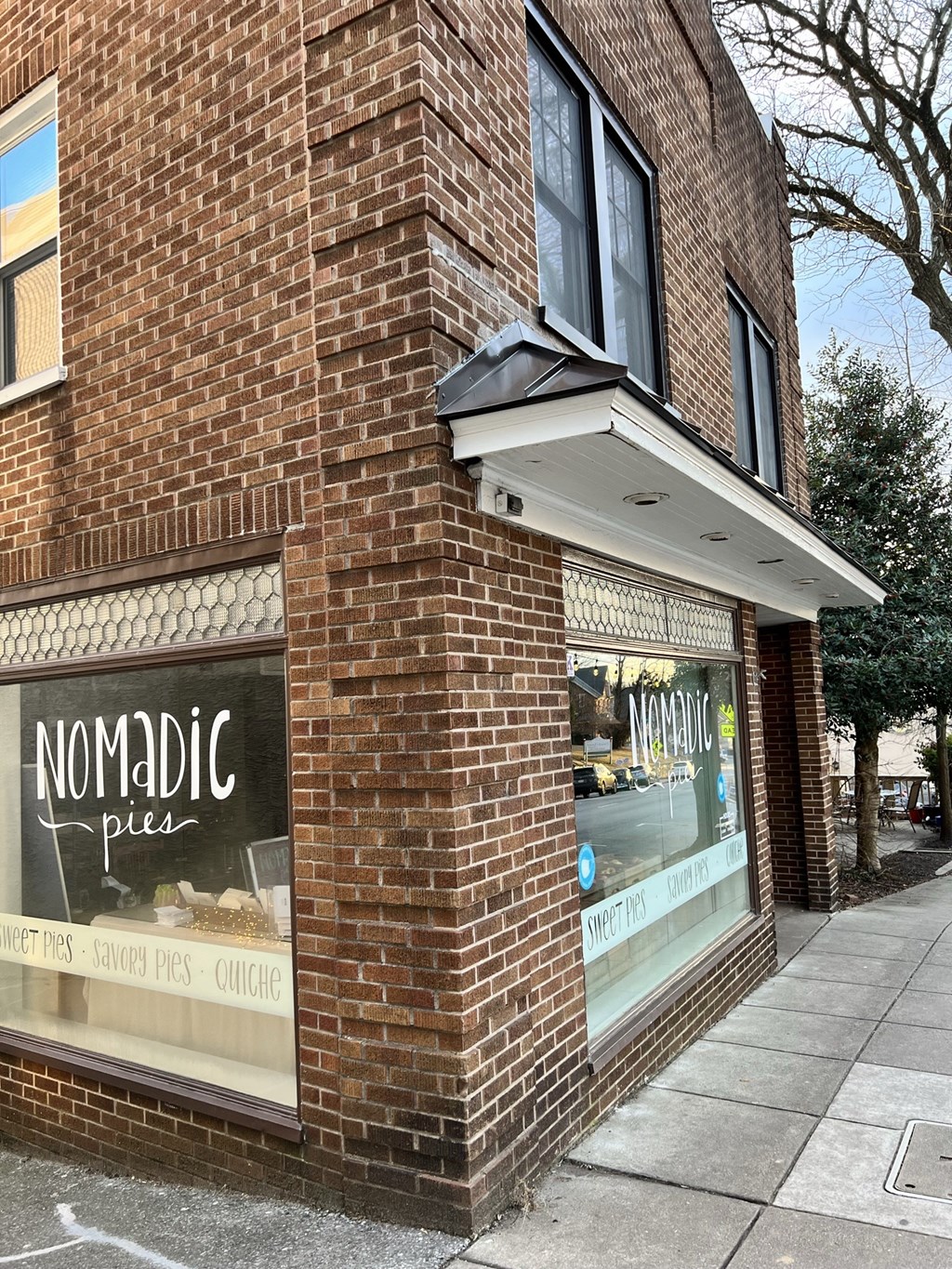 the outside of nomadic pizza on the side of a brick building