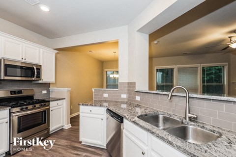 a kitchen with white cabinets and granite counter tops
