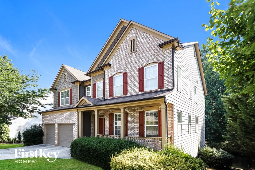 a white brick house with red shutters and a lawn