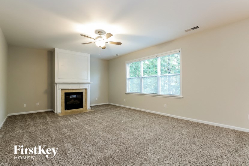 an empty living room with a fireplace and a ceiling fan