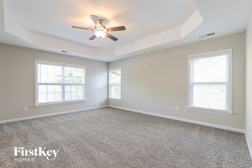 an empty living room with a ceiling fan and two windows