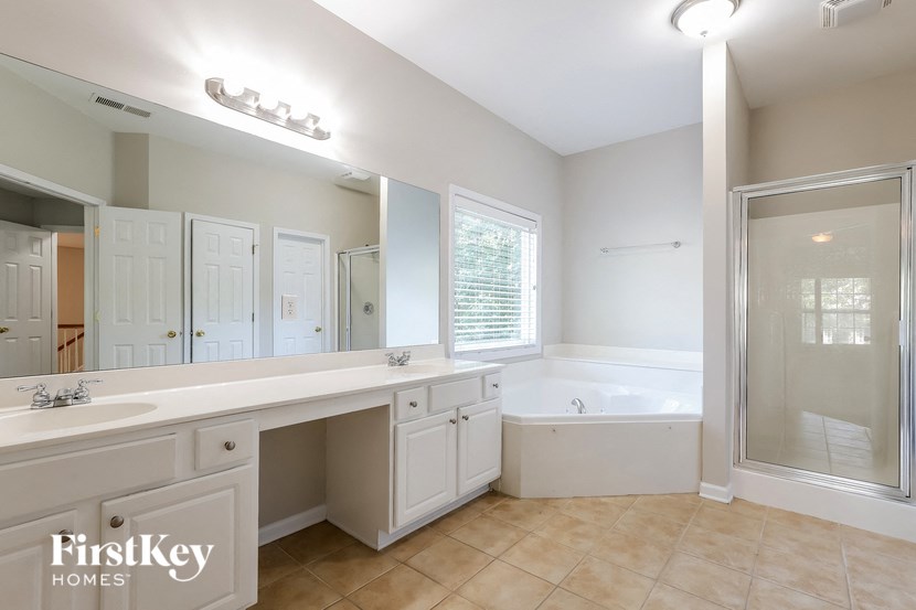 a large white bathroom with a tub and a sink and a mirror