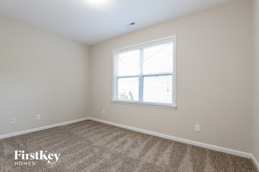 a bedroom with a window and a carpeted floor