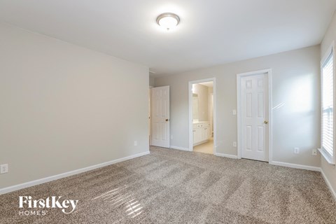 a spacious living room with carpet and a door to the bathroom