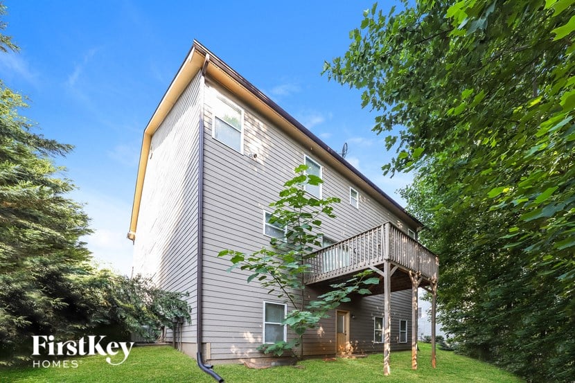 the back of the house with a deck and a tree