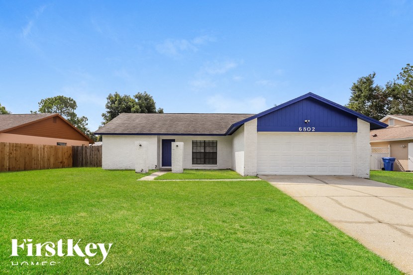 a white and blue house with a yard and a blue sky