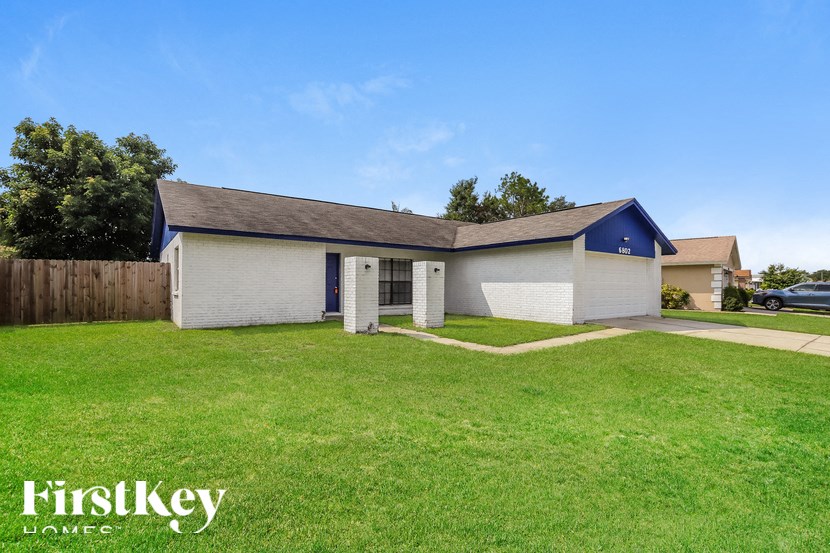 a small white house with a yard and a blue sky