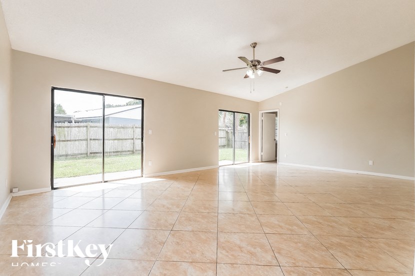 an empty living room with a ceiling fan and sliding glass doors