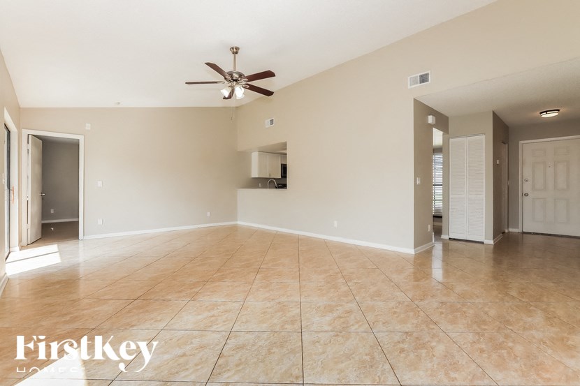 an empty living room with a ceiling fan and tile floor