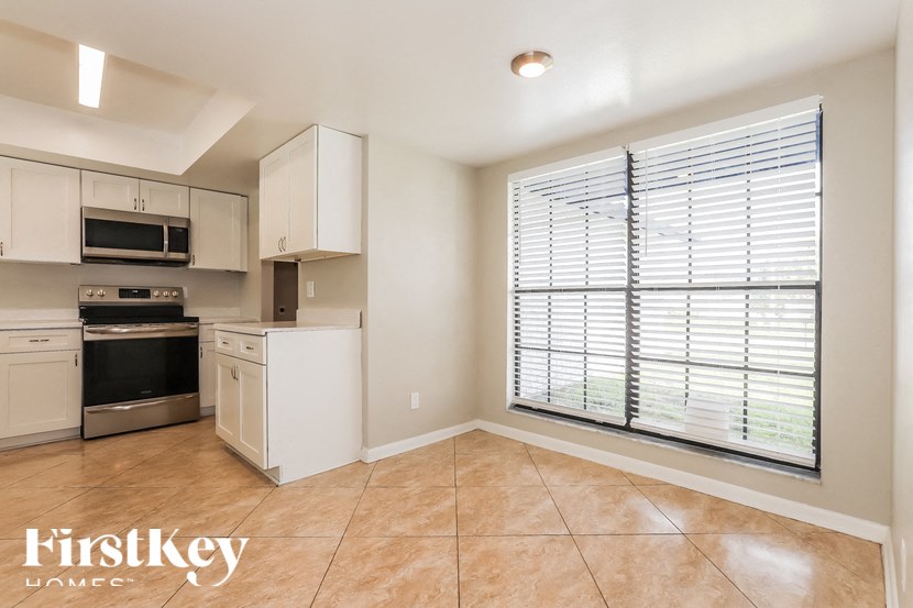 an empty kitchen with a large window and white cabinets