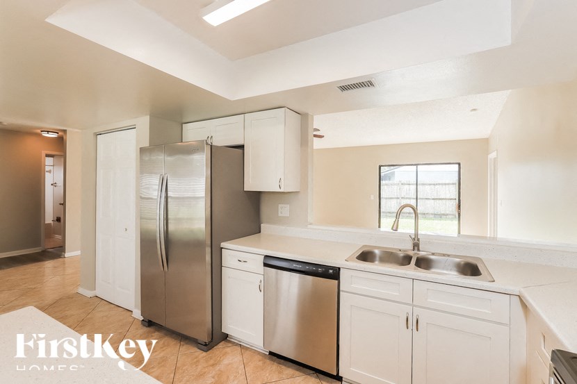 a kitchen with white cabinets and a stainless steel refrigerator