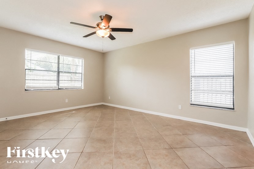 an empty living room with a ceiling fan and tiled floors