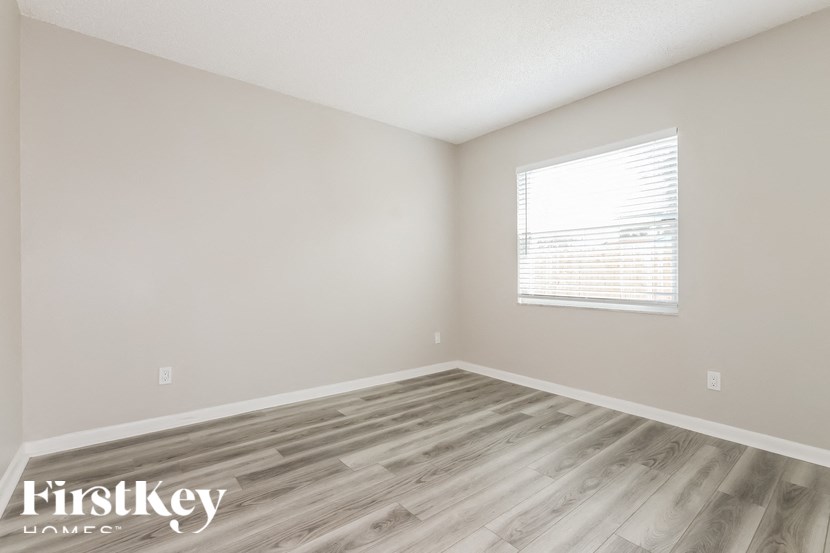 a bedroom with wood flooring and a window