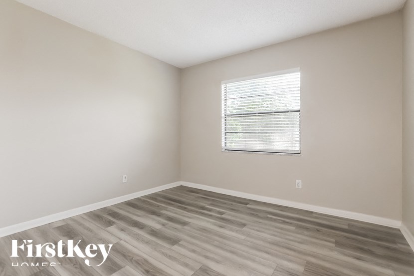 a bedroom with wood flooring and a window