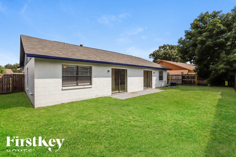 the backyard of a white house with a yard and grass