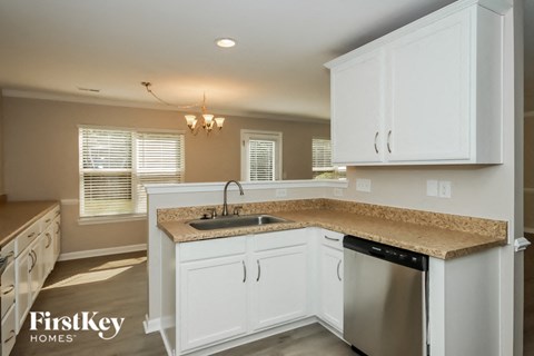 A kitchen with white cabinets and a granite countertop.