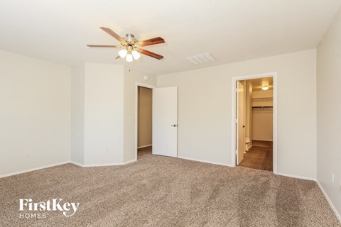 a spacious living room with carpet and a ceiling fan