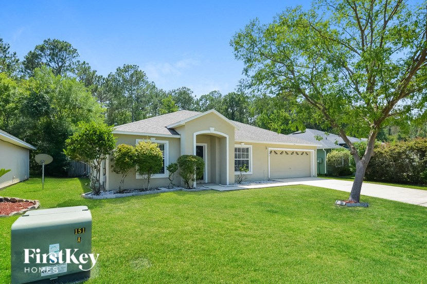 A house with a well-maintained lawn and a tree in front of it.