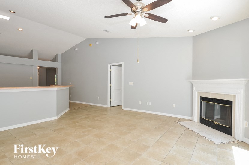 A spacious living room with a fireplace and a ceiling fan.
