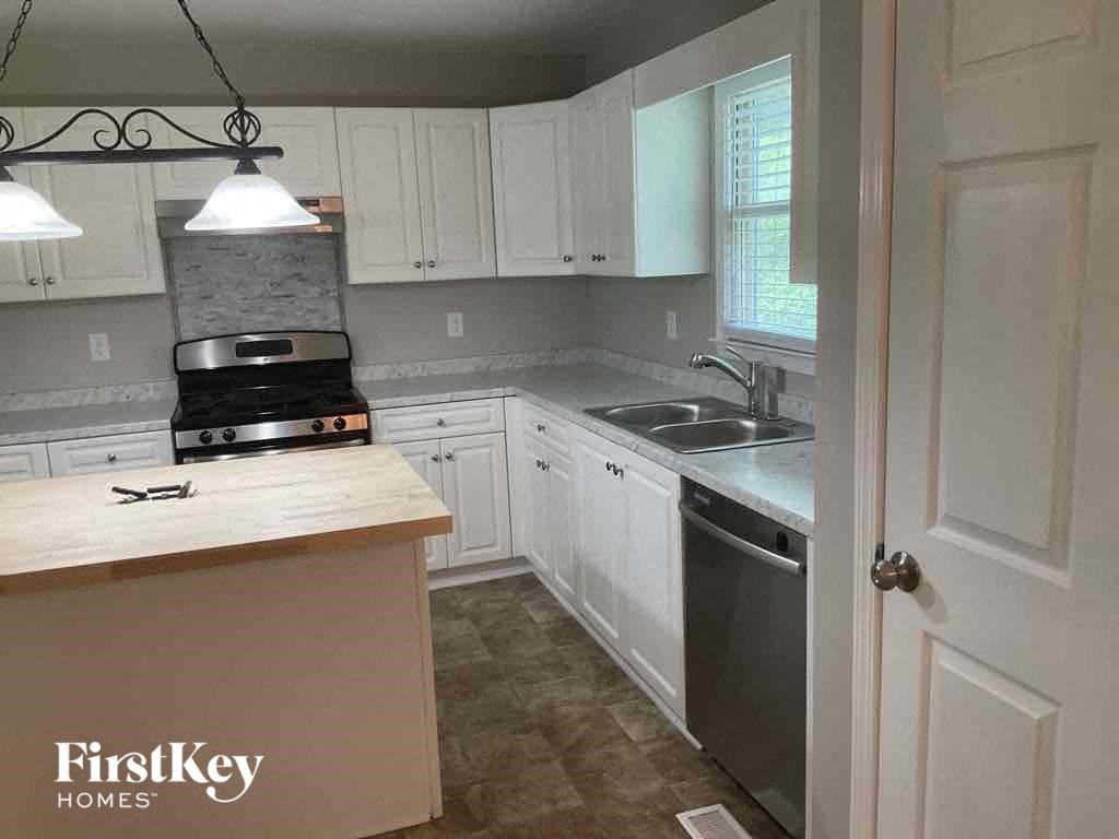 A kitchen with a stove, sink, and cabinets.