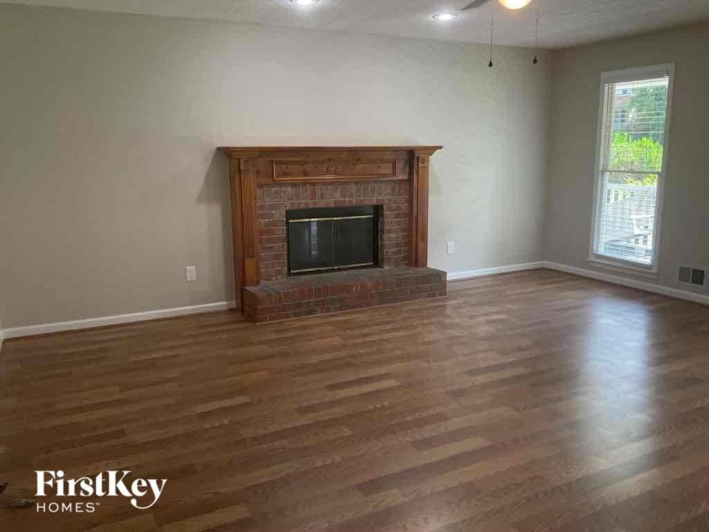 A living room with a fireplace and wooden floors.