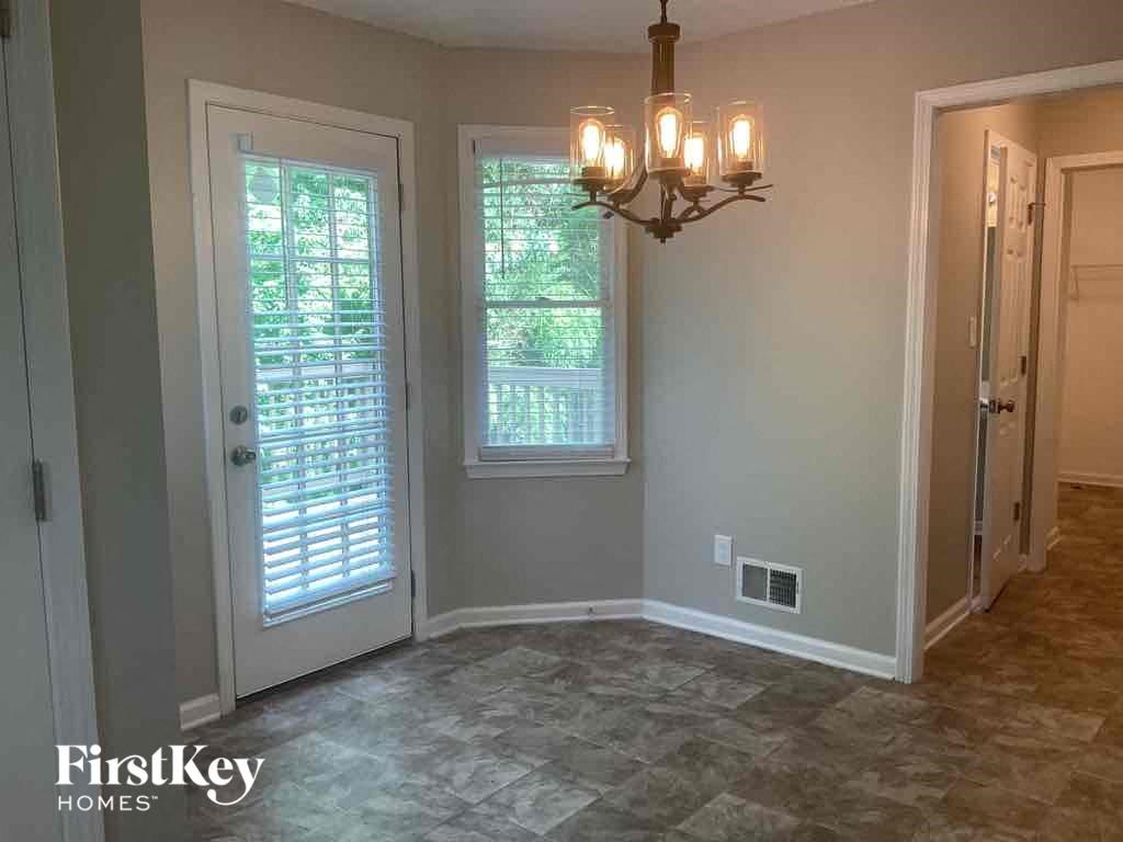 A room with a chandelier, two windows, and a door.