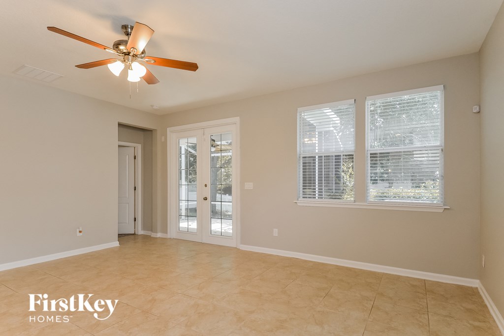 an empty living room with a ceiling fan and windows