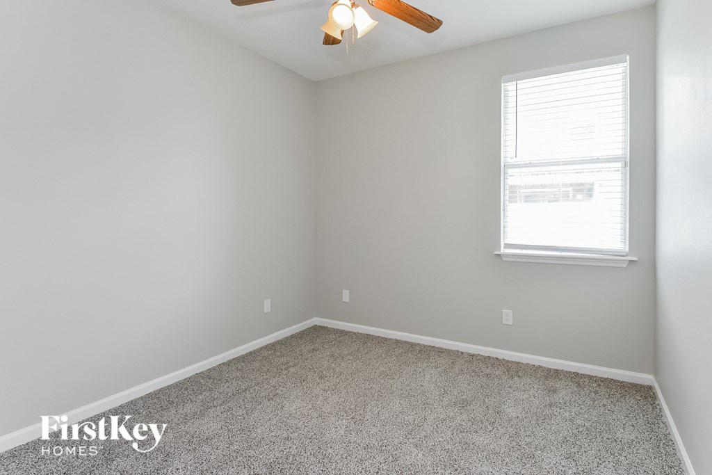 a room with carpet and a window and a ceiling fan