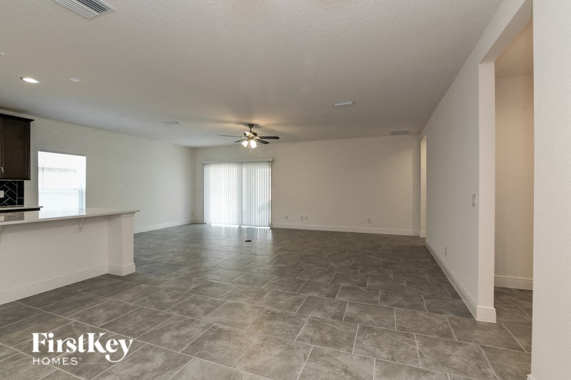 an empty living room and kitchen with a ceiling fan