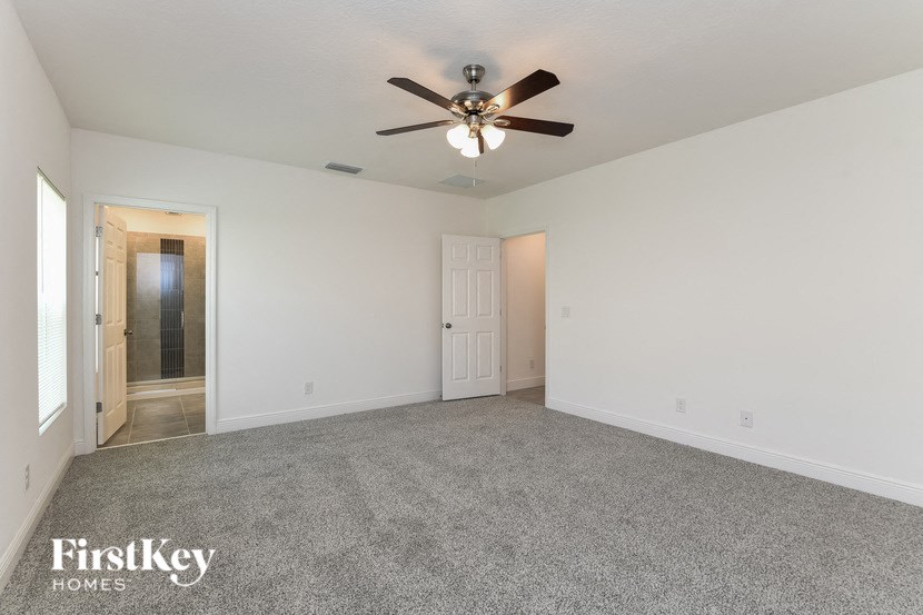 an empty living room with a ceiling fan and white walls