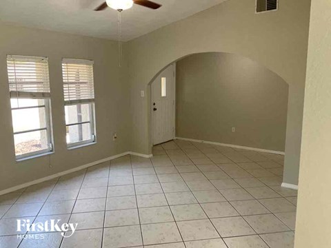 an empty living room with a ceiling fan and a tiled floor