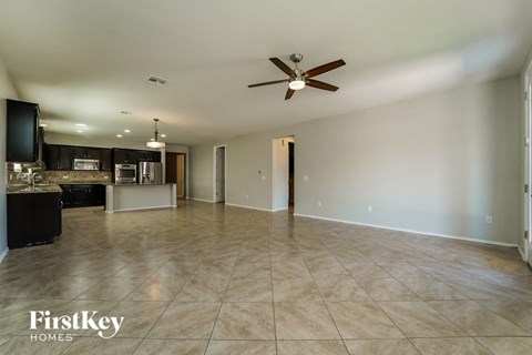 an empty living room and kitchen with a ceiling fan