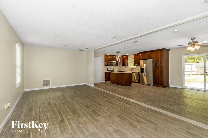 an empty living room and kitchen with wood flooring