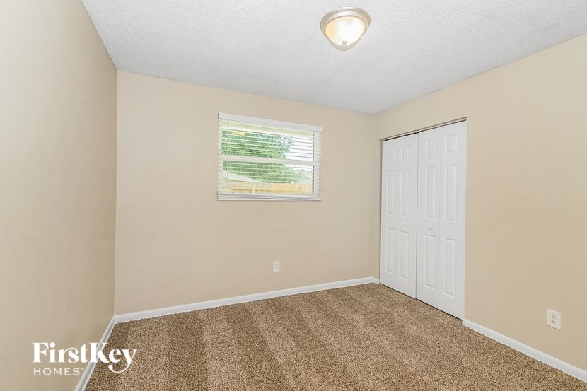 a bedroom with carpet and a window and a white door