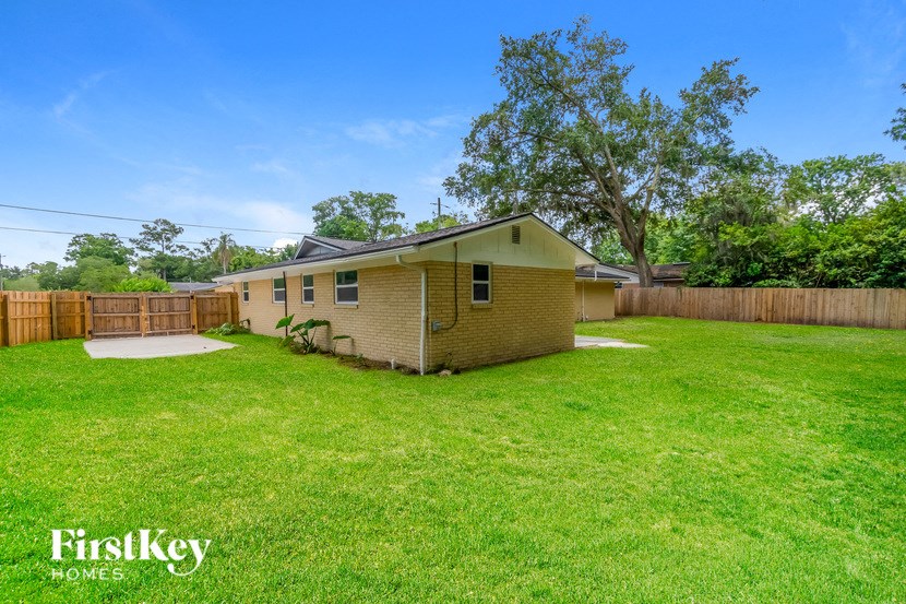 a small yellow house in a backyard with a yard and a fence