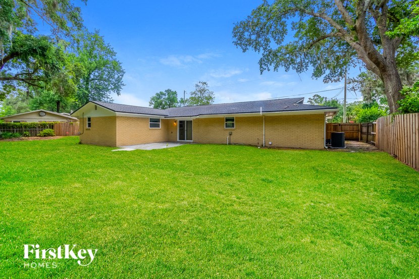 a yellow house with a grassy yard and a fence