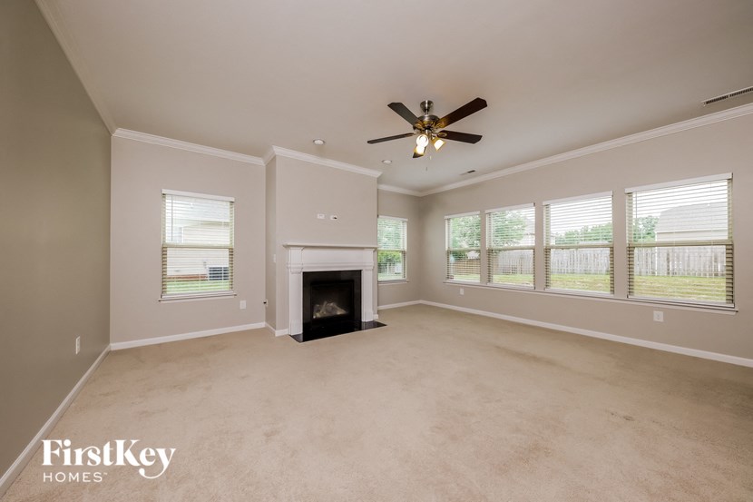 an empty living room with a fireplace and a ceiling fan