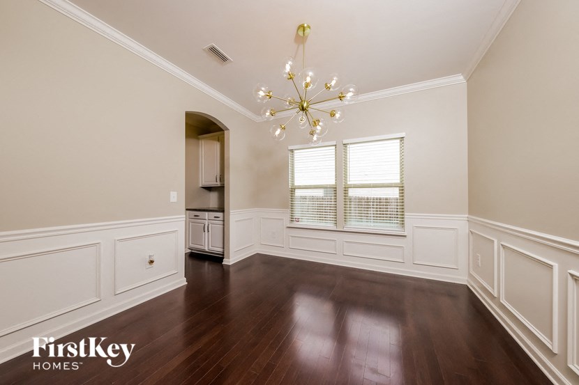a dining room with white wainscoting and a chandelier