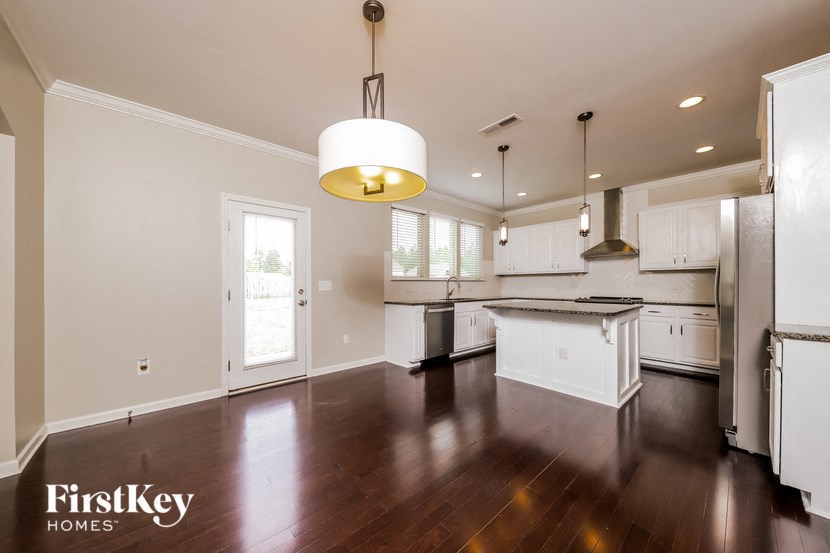 an empty kitchen with white cabinets and a wood floor