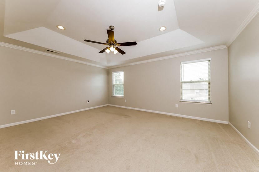 a living room with a ceiling fan and a carpet