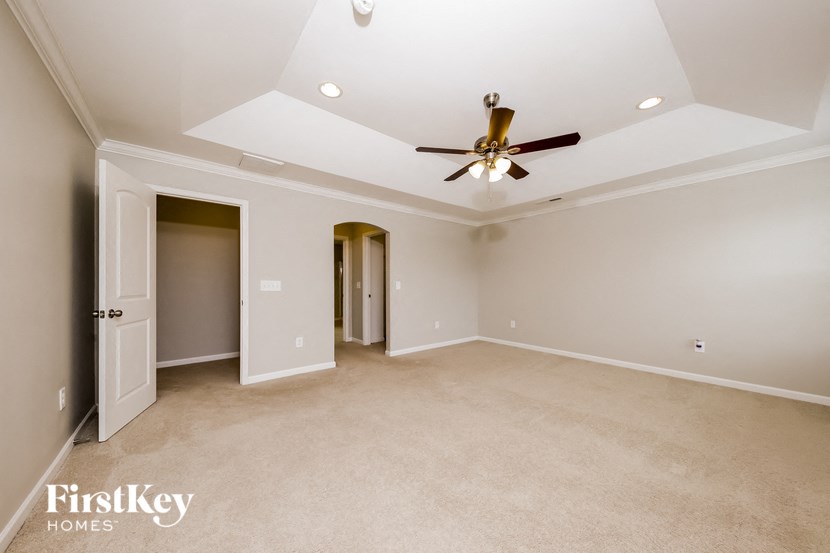 a empty living room with a ceiling fan and a door to a closet