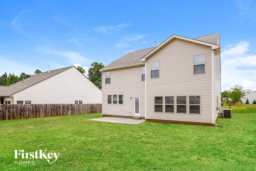 a backyard with a white house and a wooden fence