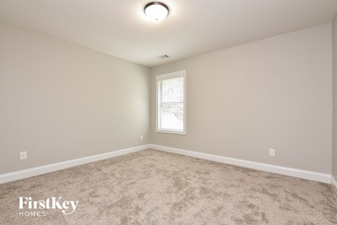 the spacious living room with carpeting and a window