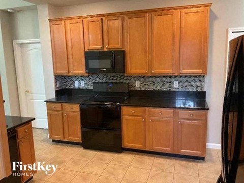 A kitchen with wooden cabinets and black countertops.