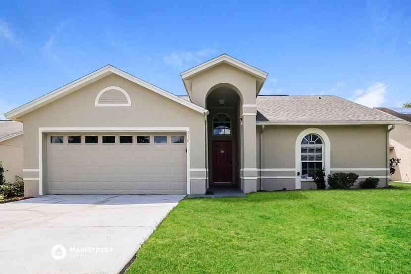 a beige house with a garage door and a lawn