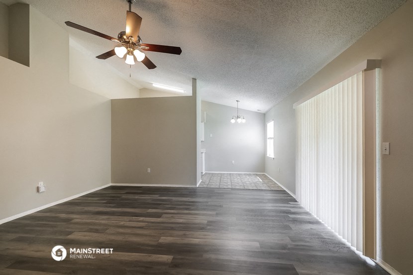 an empty living room with wood floors and a ceiling fan