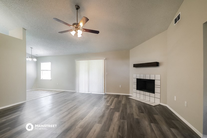 an empty living room with a ceiling fan and a fireplace