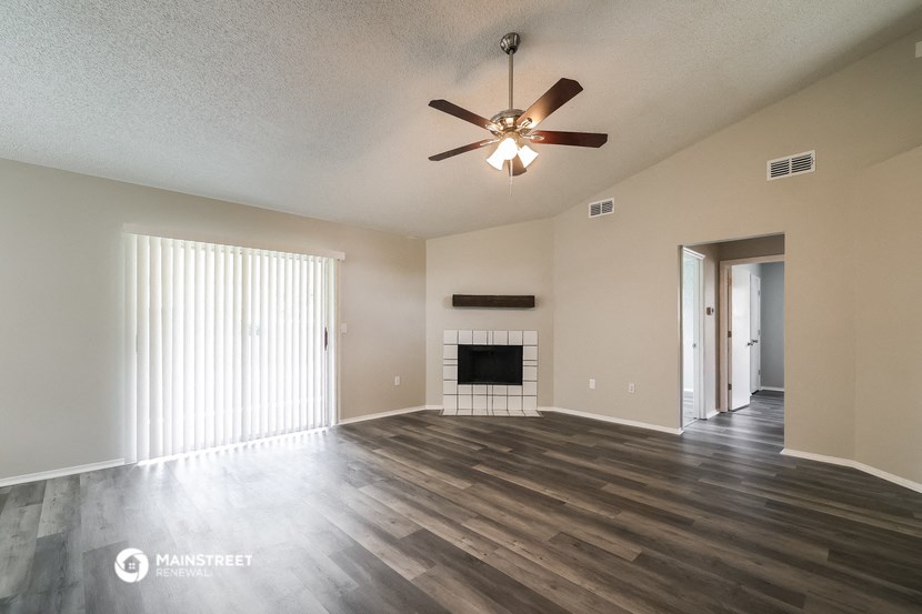 the spacious living room with fireplace and ceiling fan