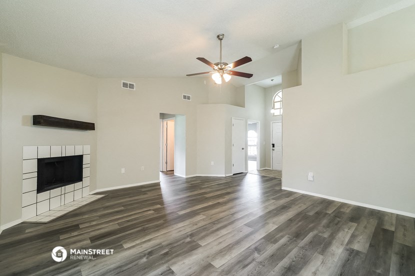 an empty living room with a ceiling fan and a fireplace