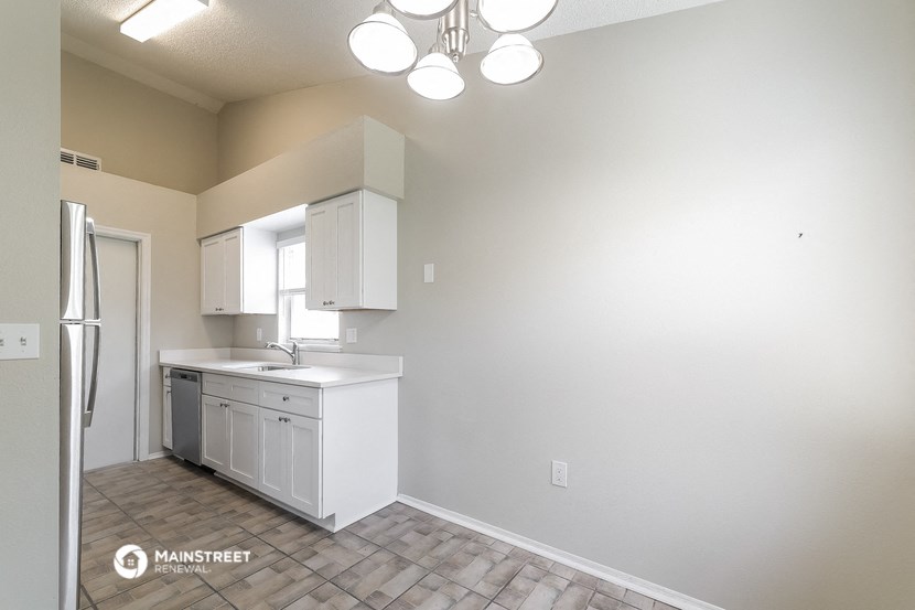 an empty kitchen with white cabinets and a stainless steel refrigerator
